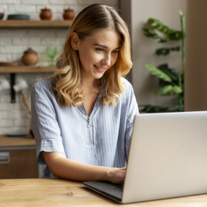 Młoda uśmiechnięta dziewczyna pracuje na laptopie.