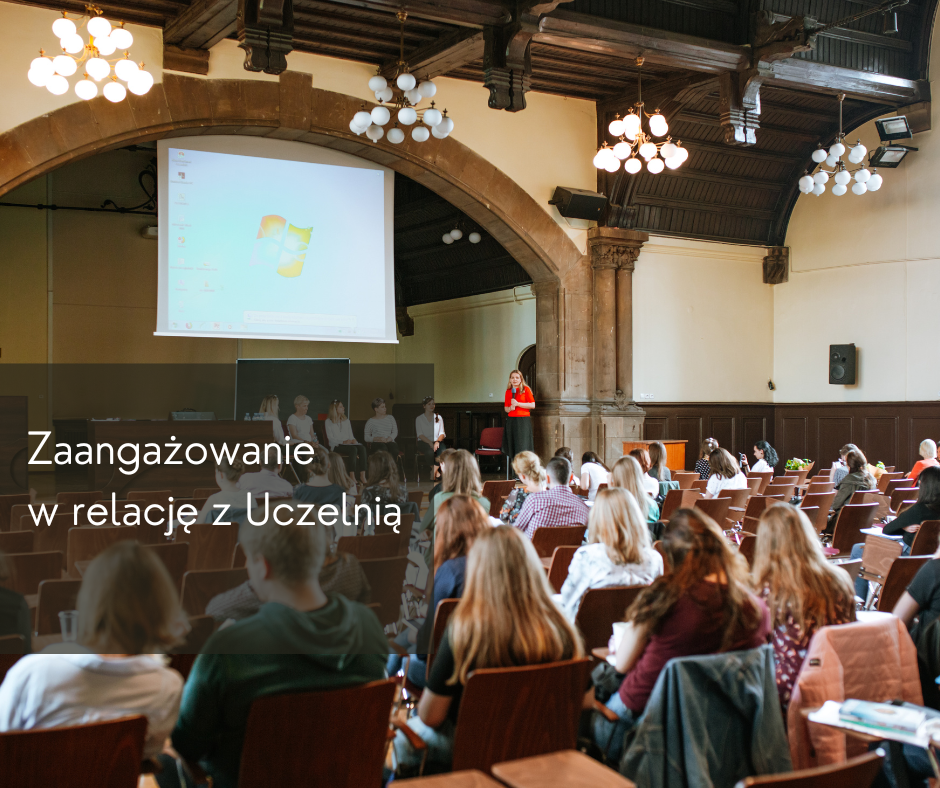 Sala wykładowa a wniej grupa ludzi siedzi na krzesłach.