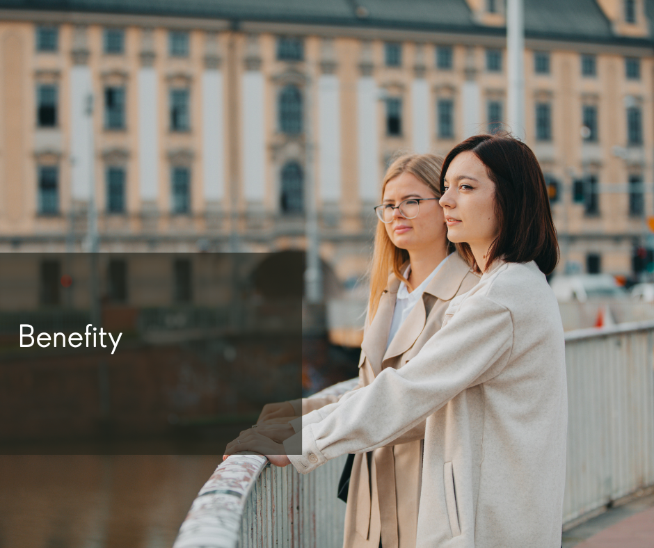 Dwie młode dziewczyny stoją na moście. W tel widać budynek Uniwersytetu