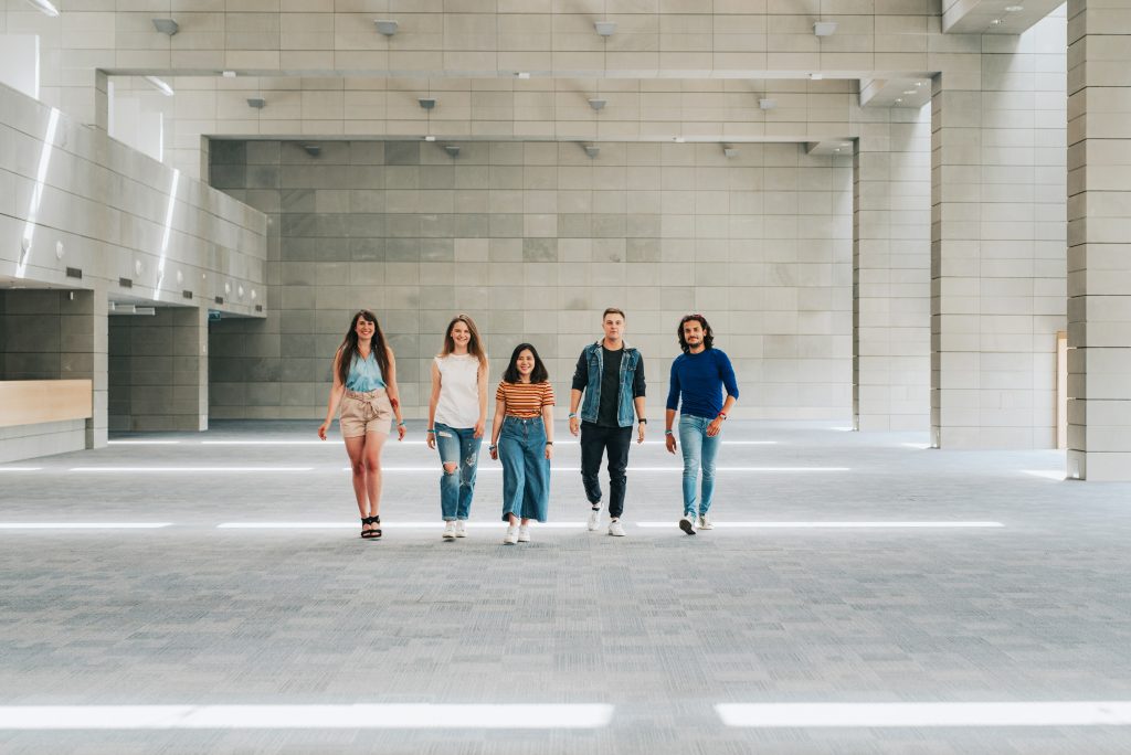 Piątka młodych ludzi idzie po betonowej podłodze.