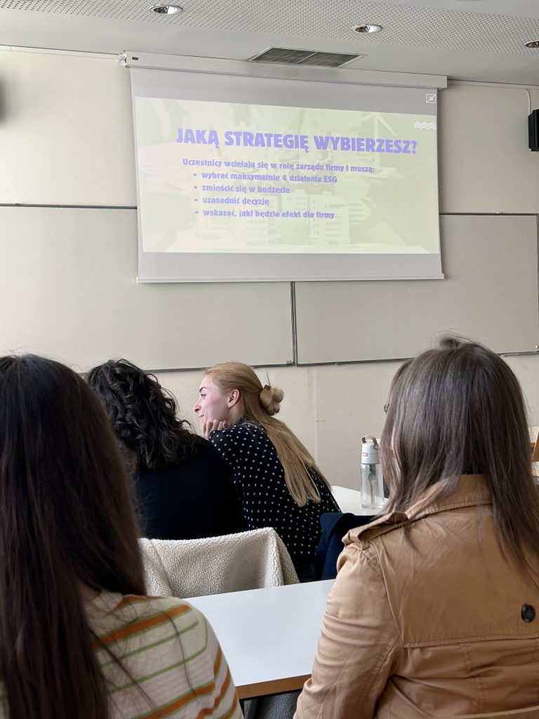 grupa słucha wykładu patrząc na prezentację z napisem Kompas ESG