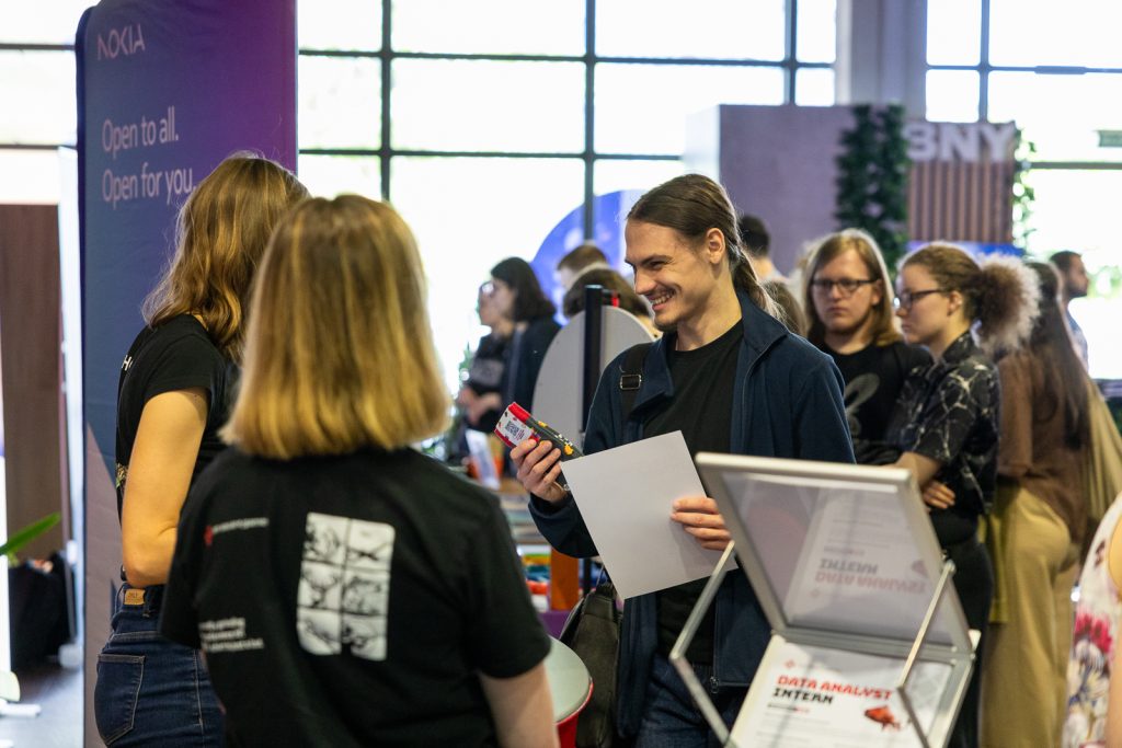 Uśmiechający się student przy stanowisku pracodawcy